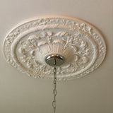 An Victorian ornate white decorative ceiling medallion with a floral relief pattern.