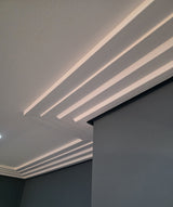 Ceiling coving with recessed lighting and a corner of a room with a dark wall.