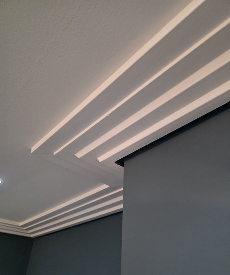 Ceiling coving with recessed lighting and a corner of a room with a dark wall.